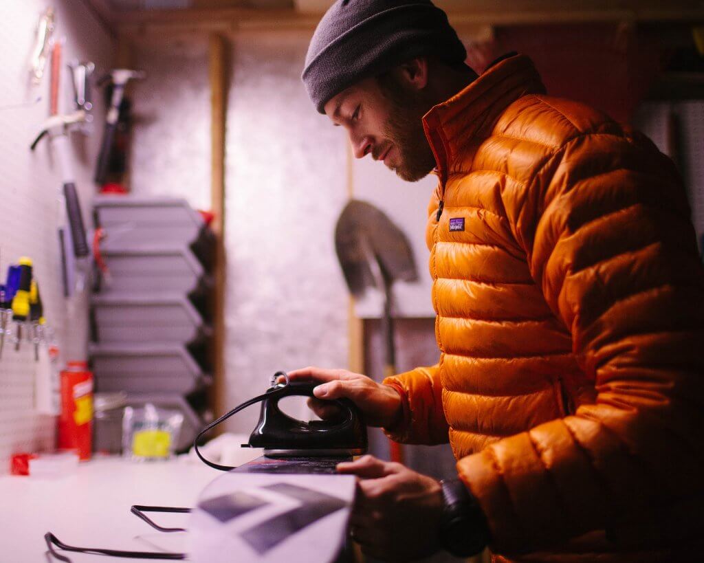 skier waxes a ski in basement