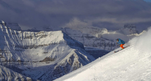 skier carving soft snow with Canadian Rockies behind him