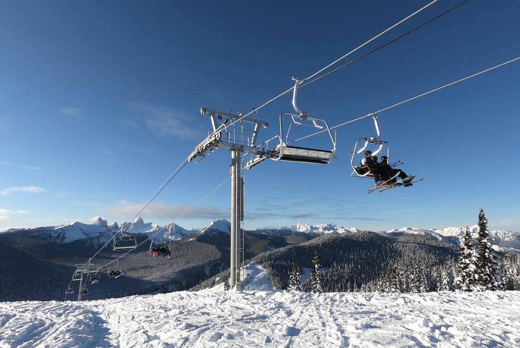 Sunny bluebird day at Manning Park Ski Resort in British Columbia with skiers and snowboarders taking chairlift