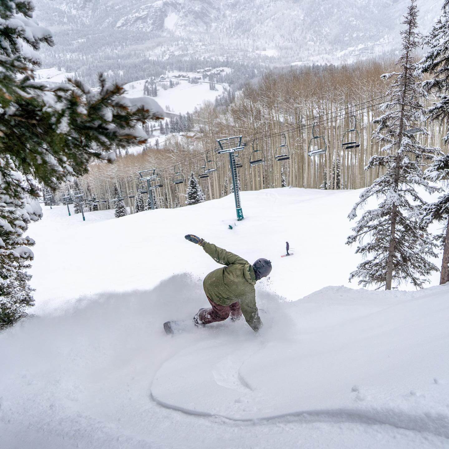 Snowboarder making a toeside slash overlooking the valley of Purgatory Resort