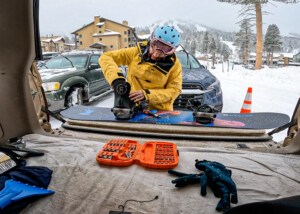 female snowboarder setting up bindings in parking lot in Lake Tahoe
