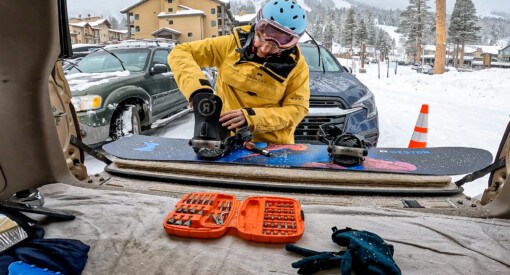 female snowboarder setting up bindings in parking lot in Lake Tahoe