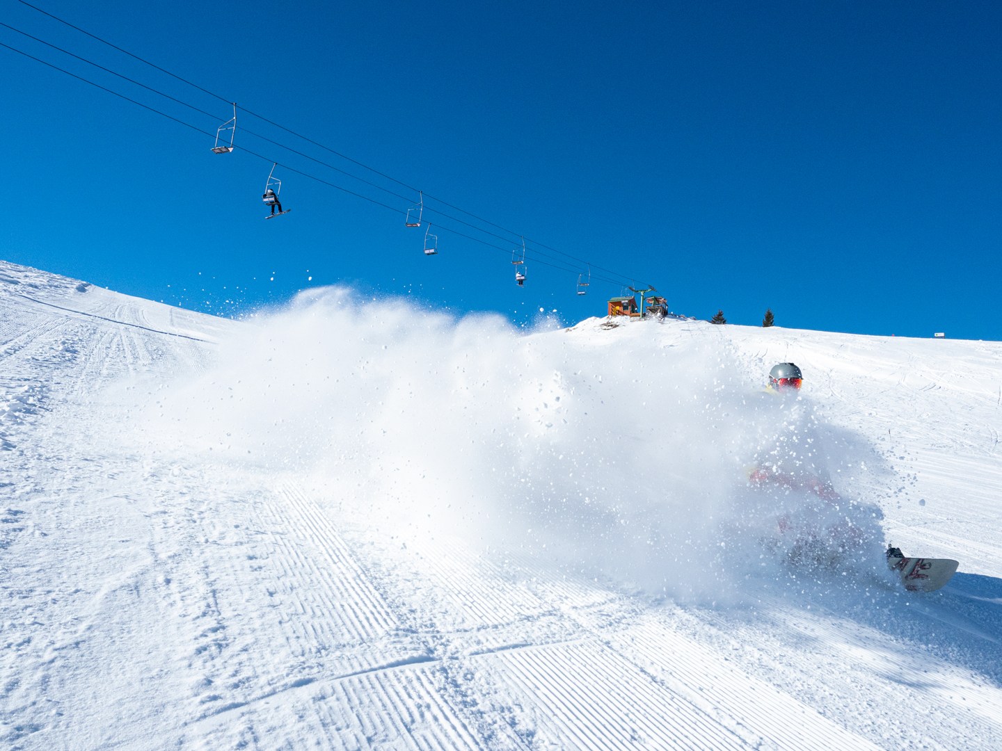 snowboarder making a heelside turn at Soldier Mountain resort creating a plume of snow