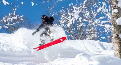 Snowboarder using Weston JaPow snowboard leaping into powder at Okunakayam Kogen Resort in Japan