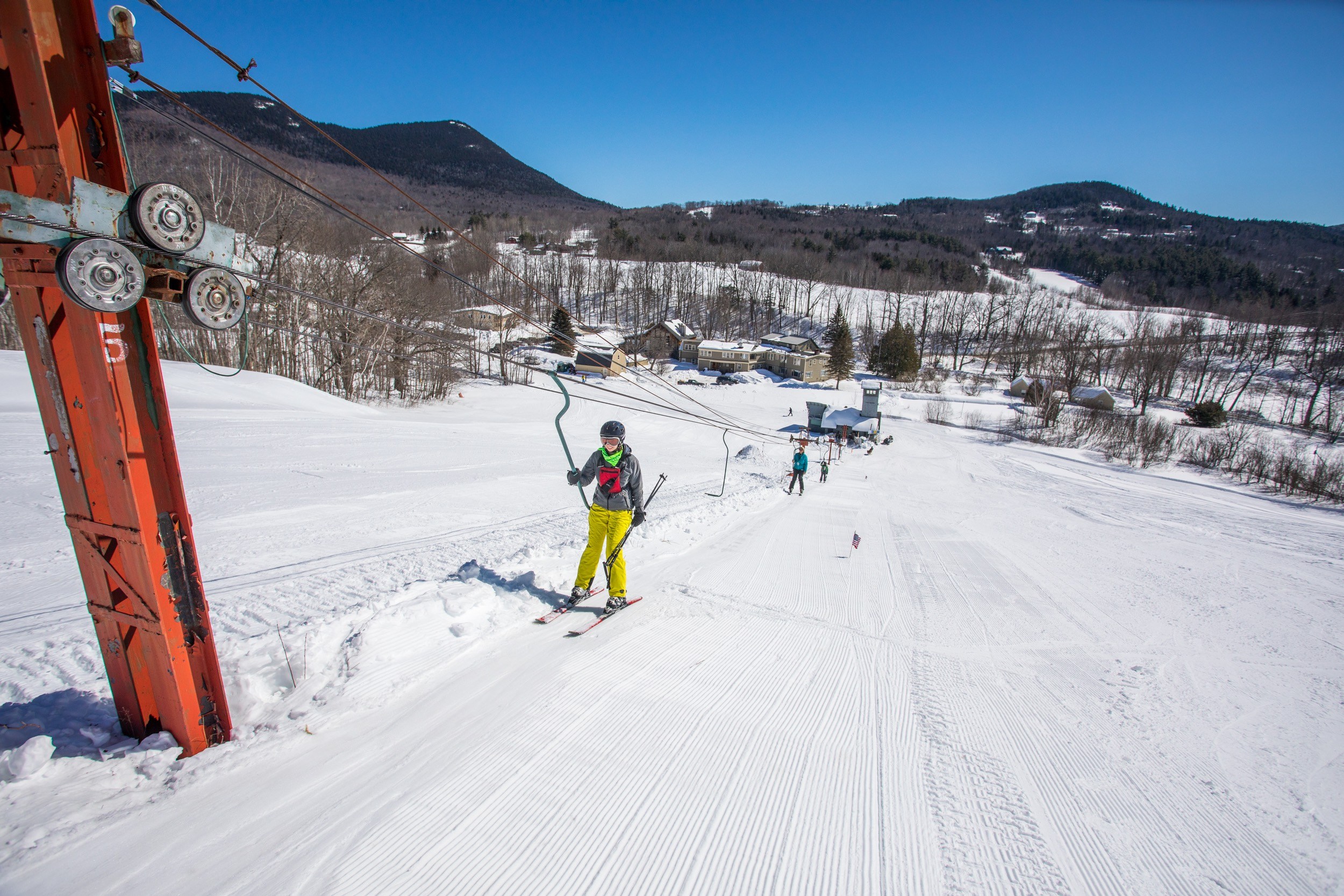 Skiers taking the J-Bar up Black Mountain Ski area on a sunny winter day