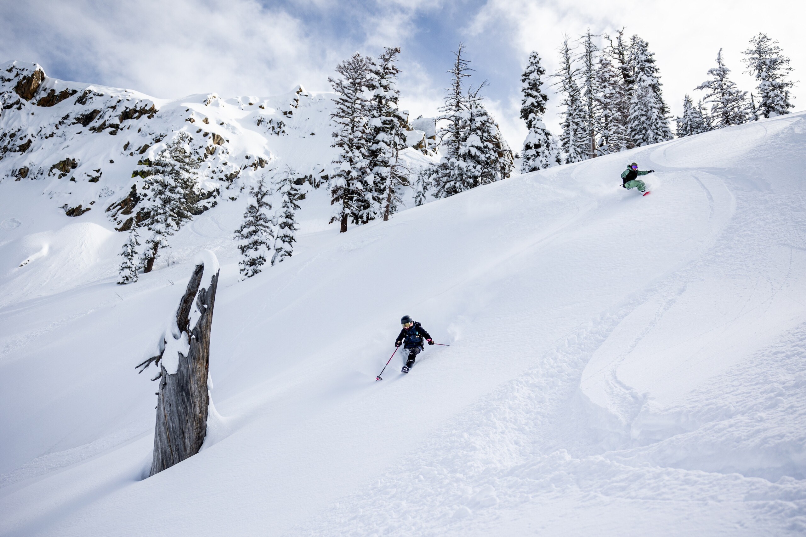 A skier and snowboarder enjoying deep pow at Bear Valley Mountain Resort just outside of Lake Tahoe