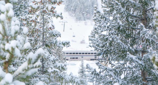 Amtrak Winter Park Express passing by Winter Park ski resort on a snowy day