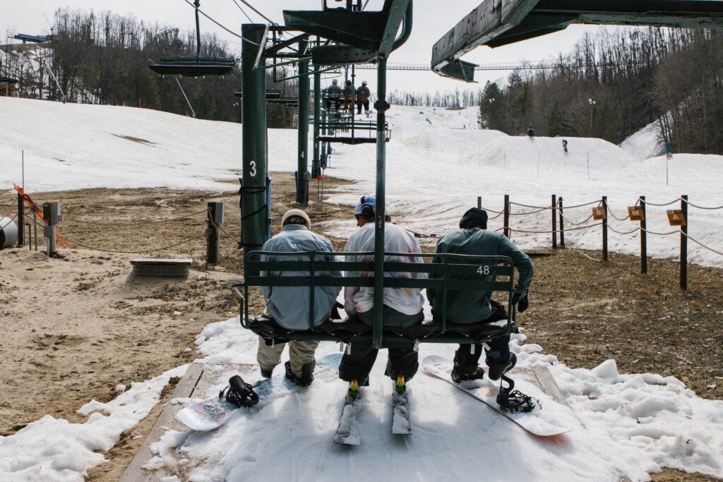 Snowboarders getting onto chairlift for late season skiing at Boyne Mountain