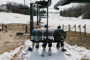 Snowboarders getting onto chairlift for late season skiing at Boyne Mountain