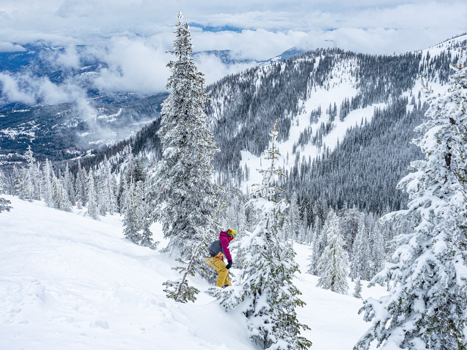 Snowboarder riding down a slope at RED Mountain Ski Resort