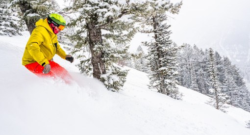 Snowboarder carving through fresh powder at Grand Targhee Resort in Wyoming